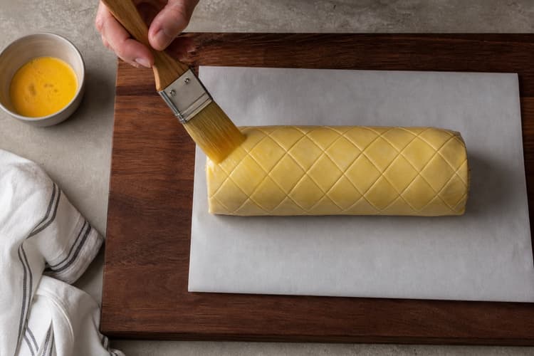 Beef Wellington method step 6, Wrap cold pastry and chill again: The pastry is cold and firm, lies smoothly against the cylinder, and has a neat underside seam with no thick folded ends.