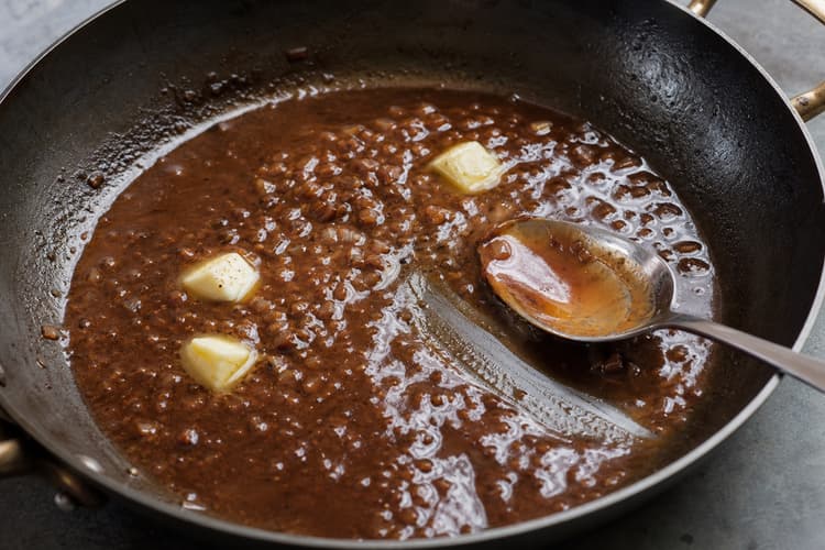 Bistro Steak & Eggs with Shallot Jus method step 4, Reduce and mount the shallot jus: The jus coats a spoon continuously and a finger trail stays clean.
