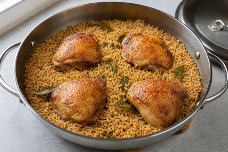 One-Pan Chicken and Crispy Rice method step 4, Start measured covered absorption: The liquid is boiling before the covered pan enters the oven and every chicken skin sits above the liquid line.