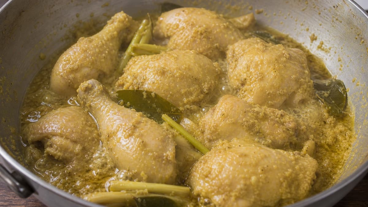 Ayam Goreng Kalasan, step 2, Ungkep at a quiet simmer: Tan-gold liquid quivers gently; chicken is 75°C+, tender at the joint, and still firmly attached to bone.