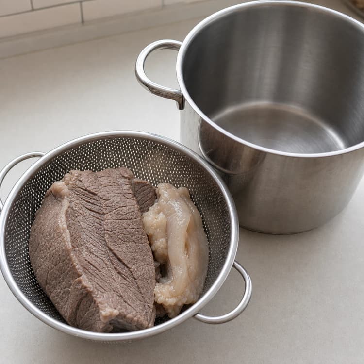 Easy Gomtang method step 1, Soak, blanch, and reset the pot: Beef surfaces are clean grey-brown with no beige foam or dark clots, and the pot has no residue.