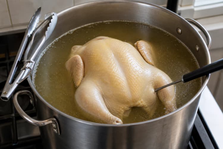 Hainanese Chicken Rice method step 2, Scald, poach, and verify both thick sections: Skin is taut and intact, the cavity has flushed hot, and both breast and thigh verify at least 75°C.