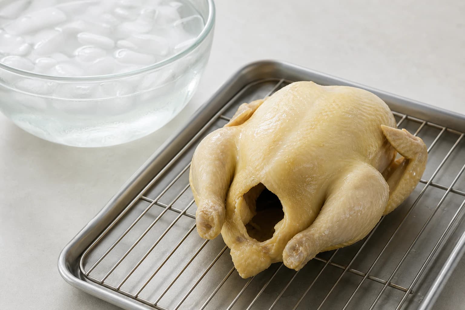 Hainanese Chicken Rice, step 3, Stop carryover, drain, and protect the skin: The skin is smooth, taut, and dry with a fine gelatinous layer instead of chalky waterlogged patches.