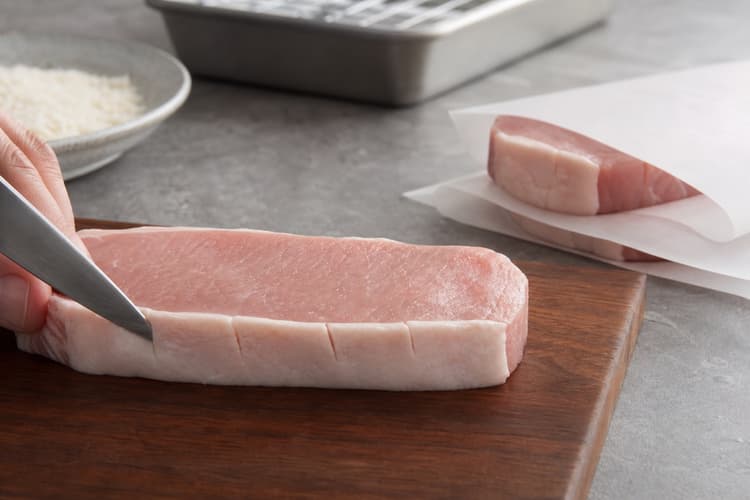 Japanese Pork Tonkatsu method step 2, Score and even the thick pork: Each chop is a flat, even oval with no tight fat band and remains visibly thick rather than schnitzel-thin.