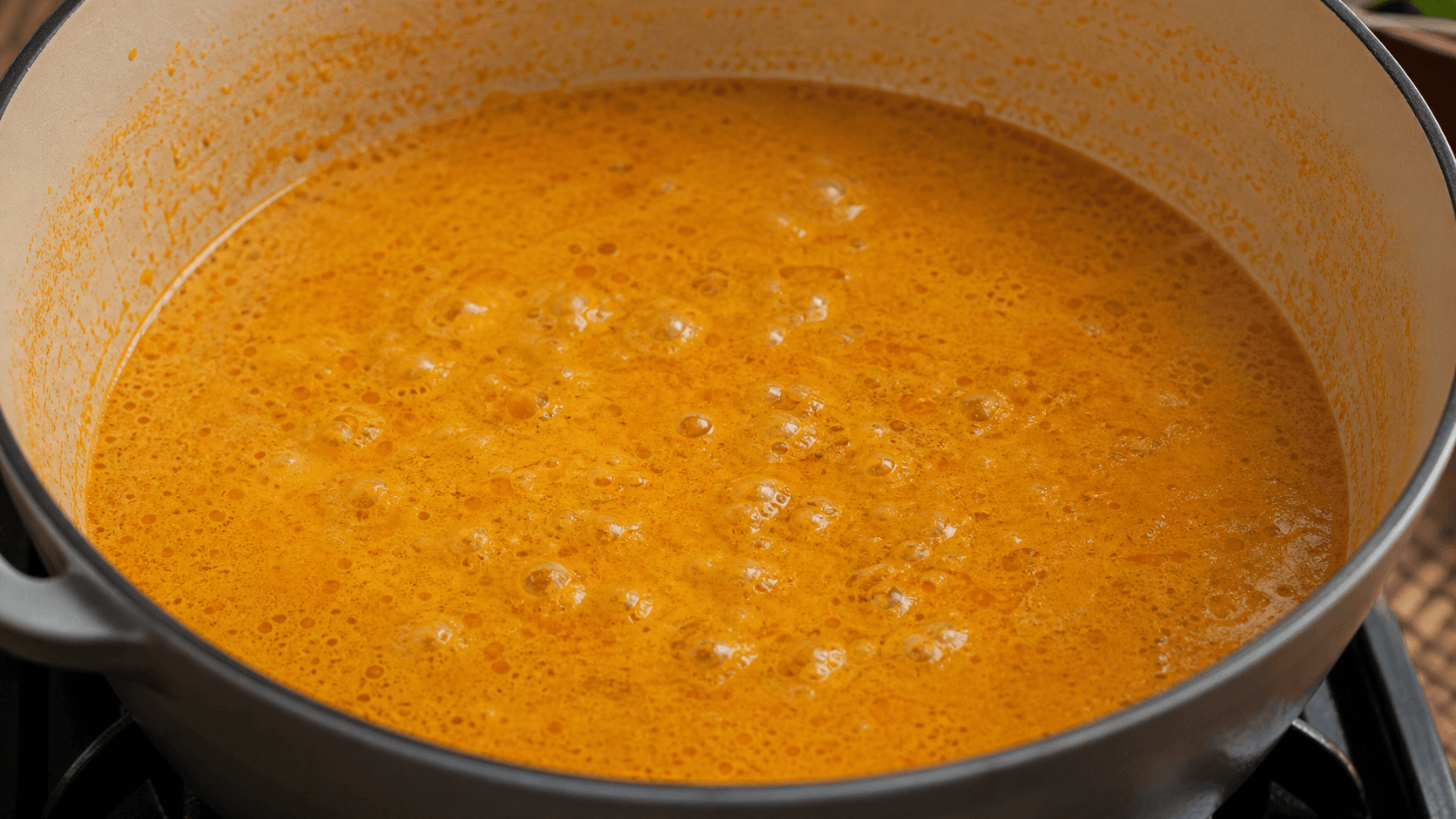 Laksa Lemak, step 3, Simmer broth: Opaque orange broth with a small surface shimmer.