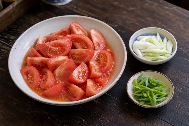 Tomato Egg Stir-Fry method step 1, Cut tomatoes without losing their juice: Plump tomato wedges sit in their own juice, with white and green scallion parts held separately.