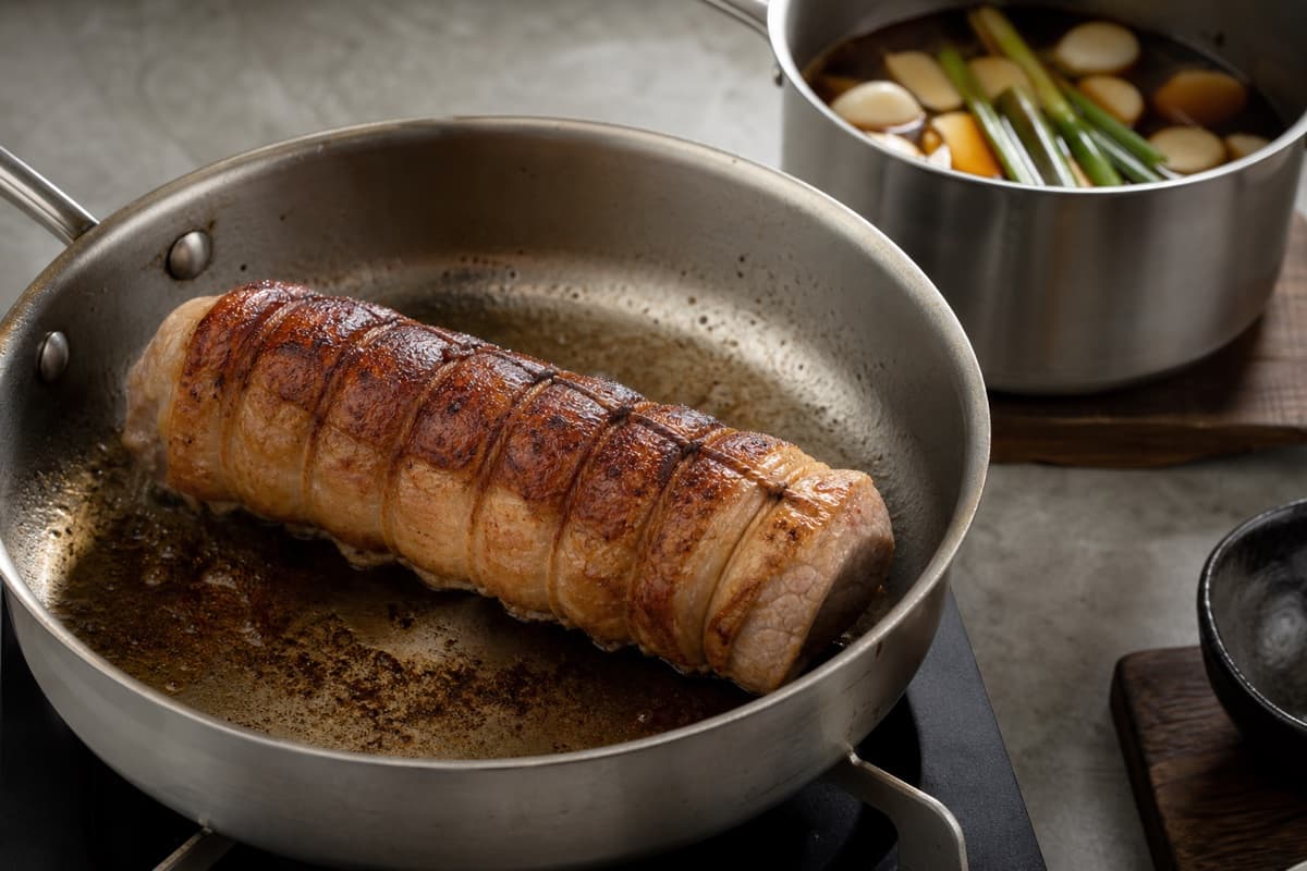 Tonkotsu Shoyu Ramen, step 2, Roll, sear, and begin the chashu: The tied cylinder stays intact, feels tender to a probe at 90–93°C, and later cuts cold into clean spirals with a glossy brown edge.